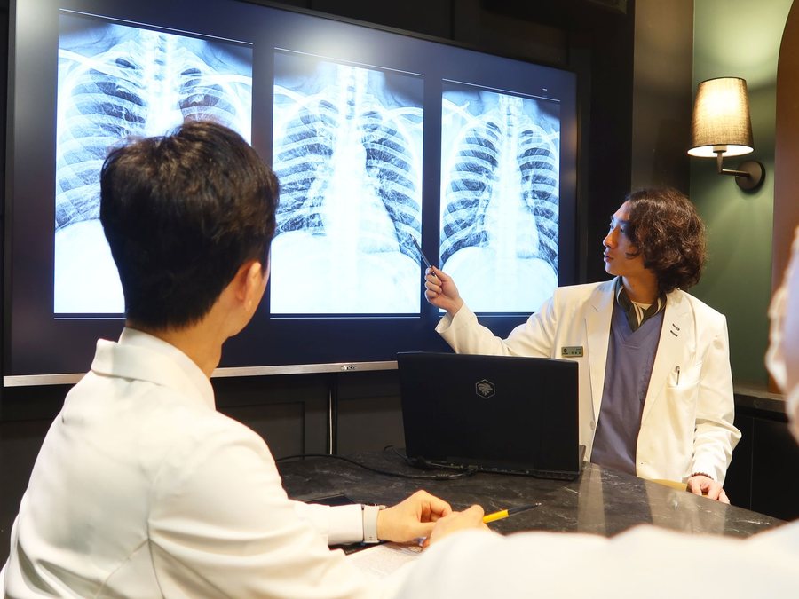 진료실에서 X-ray 영상을 보며 설명하는 모습 — 영상검사와 한의·의과 협진이 한 곳에서 이어집니다