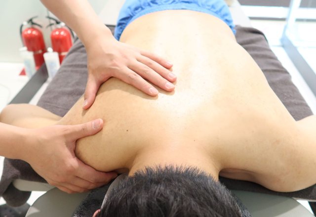 치료사가 엎드린 환자의 어깨와 등을 손으로 누르는 도수치료