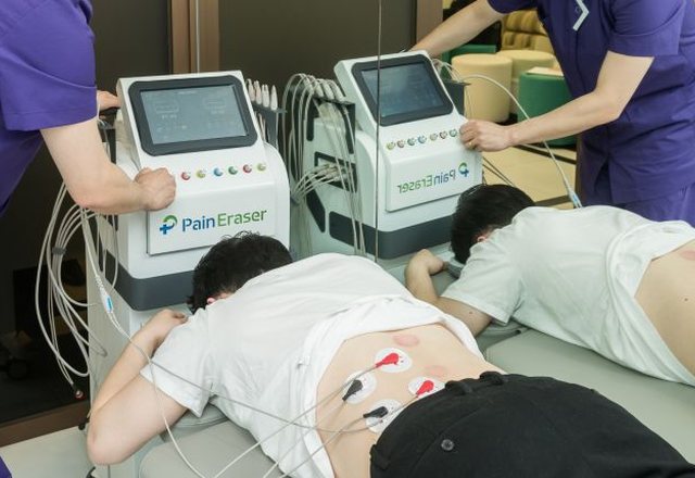 허리에 패드를 붙여 물리치료 기기로 치료받는 모습